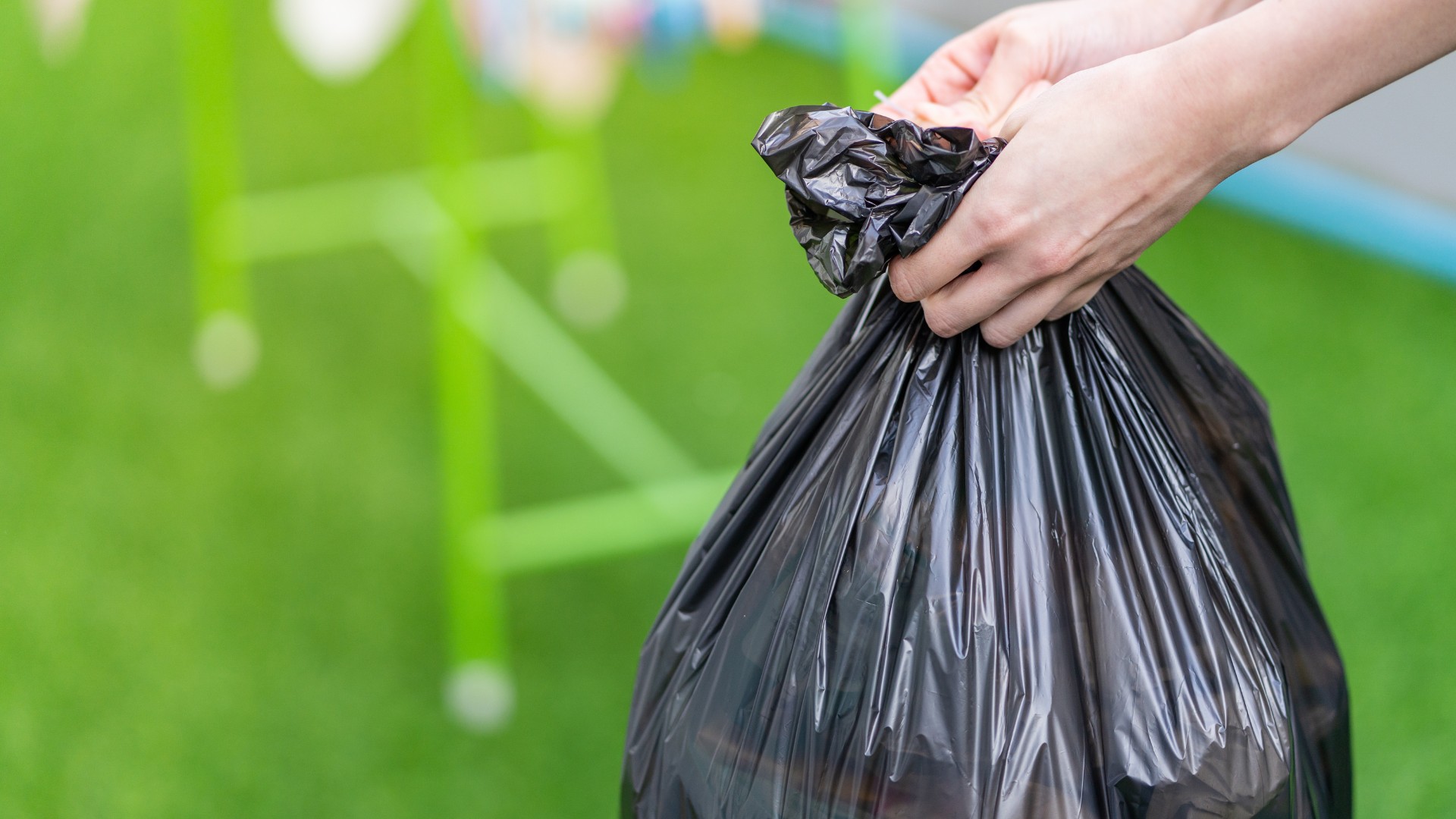 A hand removing a bag of garbage.